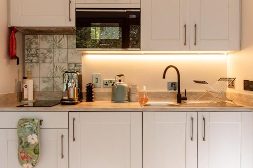 a kitchen with white cabinets and a sink at Burrenmore Nest - Luxury Forest Lodges with Hot Tubs & Sauna in Castlerock