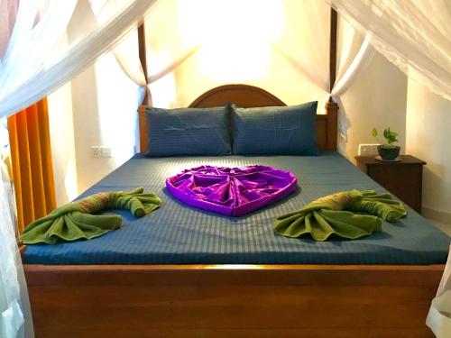 ein Bett mit zwei Kissen und einem lila Kleid darauf in der Unterkunft Dream Villa in Batigama