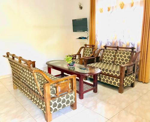 ein Wohnzimmer mit Stühlen, einem Tisch und einem Sofa in der Unterkunft Dream Villa in Batigama