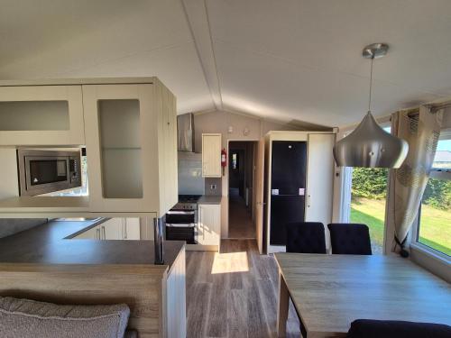 a kitchen and living room with a table and chairs at Harries Superior Lodge Ocean in New Quay