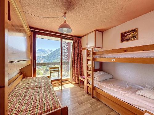 1 Schlafzimmer mit 2 Etagenbetten und einem großen Fenster in der Unterkunft Appartement confortable au pied des pistes avec accès piscine chauffée - FR-1-267-229 in Le Corbier