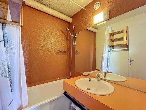 ein Badezimmer mit Waschbecken, Spiegel und Badewanne in der Unterkunft Appartement confortable au pied des pistes avec accès piscine chauffée - FR-1-267-229 in Le Corbier