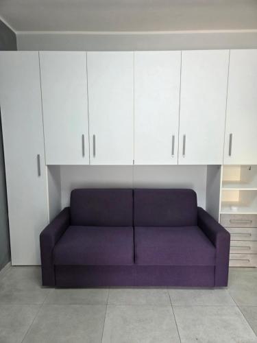 Un sofá morado en una habitación con armarios blancos. en Ceriale Suite, en Ceriale