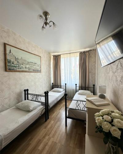 a bedroom with two beds and a table with flowers at Hotel Plazma in Lviv