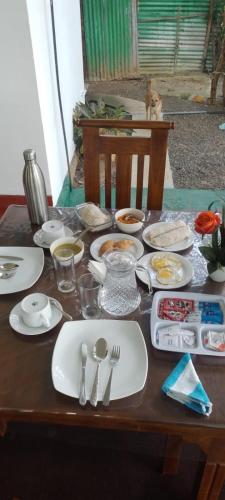 a wooden table with plates and utensils on it at Sigiriya Palace View in Sigiriya
