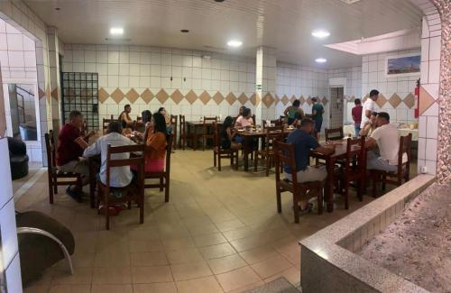 a group of people sitting at tables in a restaurant at Hotel Lídia in Fortaleza