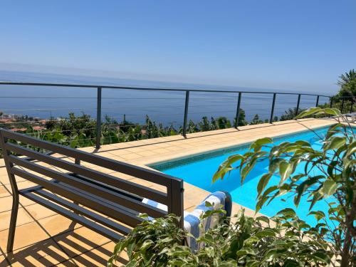 a bench sitting next to a swimming pool with the ocean at Casa Vista do Ledo in Arco da Calheta
