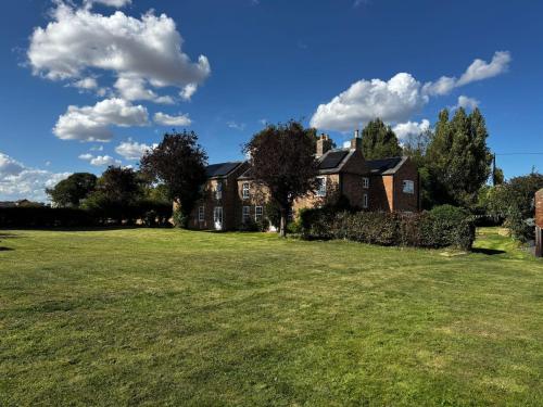 a house with a large field in front of it at Spacious 6-Bed Countryside Home Surrounded by Nature in Sutton Bridge