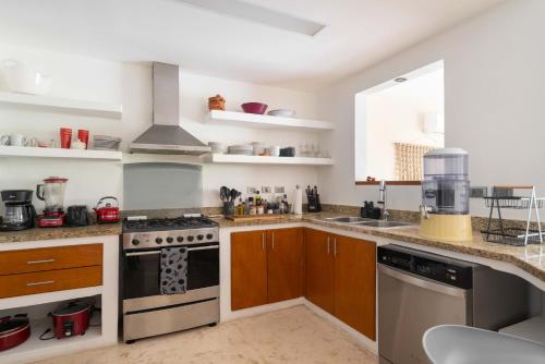 a kitchen with stainless steel appliances and wooden cabinets at Puerto Aventuras 2 Dorm-Piscina-Playa-Riviera Maya in Puerto Aventuras