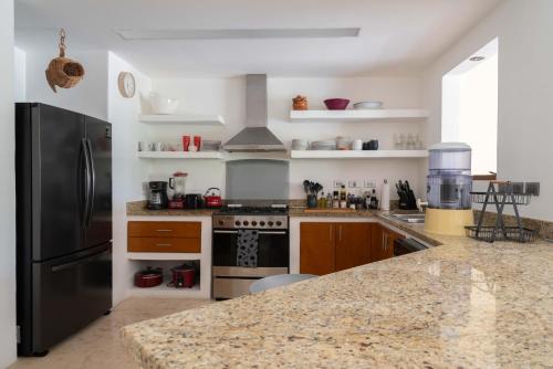 a kitchen with a black refrigerator and a granite counter top at Puerto Aventuras 2 Dorm-Piscina-Playa-Riviera Maya in Puerto Aventuras
