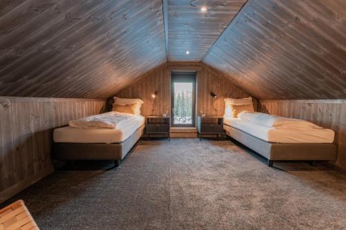 two beds in a room with wooden walls at Ski centre, sauna, hot tub in Nystølen