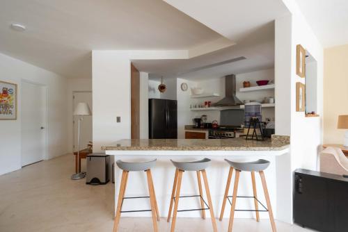 a kitchen with a counter and four stools at Puerto Aventuras 2 Dorm-Piscina-Playa-Riviera Maya in Puerto Aventuras