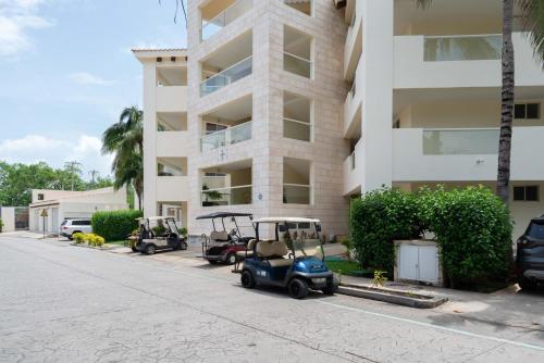 a building with three golf carts parked in front of it at Puerto Aventuras 2 Dorm-Piscina-Playa-Riviera Maya in Puerto Aventuras