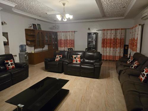 a living room with black leather couches and a table at 3 bedroom fully furnished bnb in Eldoret
