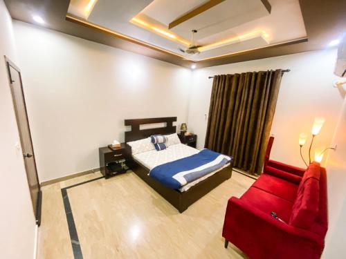a bedroom with a bed and a red couch at Sahiwal family Guest house in Gurmukh Singhwāla