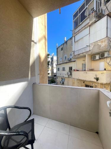 a chair on a balcony with a view of a building at Zan in Netanya