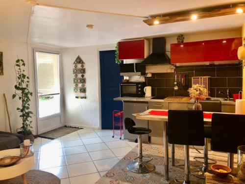 una cucina con armadi rossi e un tavolo con sedie di Appartement Yucca entre Mer Montagne a Pérols