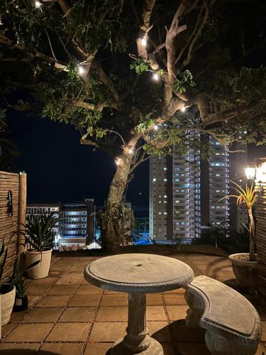 a stone table in front of a tree with lights at Ocean Village in Amanzimtoti