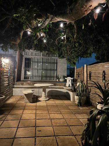 a patio with a table and a bench under lights at Ocean Village in Amanzimtoti
