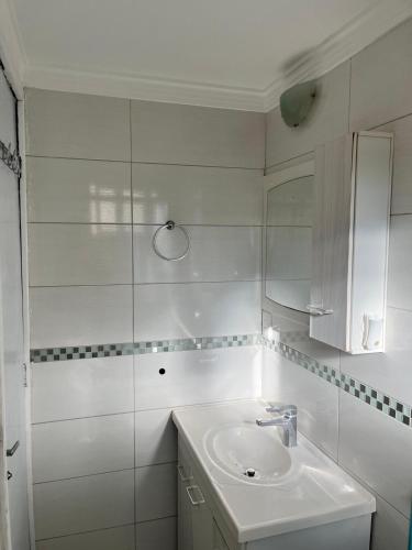 a white bathroom with a sink and a mirror at Apartamento próximo ao Shopping Catuaí in Cascavel