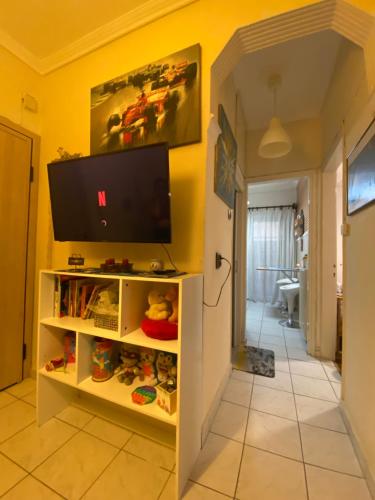a living room with a tv on a yellow wall at Queen Suites Family Friendly 60m2 in Thessaloniki