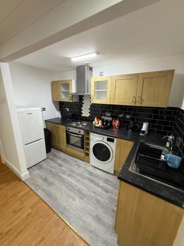 a kitchen with wooden cabinets and a washer and dryer at The Heart of Birmingham City Centre in Birmingham