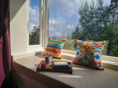 a window seat with two pillows and a tray with a book at Hope Horizon Villa Coonoor by LexStays in Coonoor