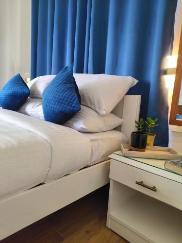 a bed with blue curtains and white pillows on it at Hope Horizon Villa Coonoor by LexStays in Coonoor