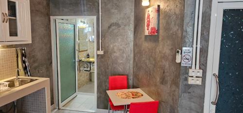 a small kitchen with a table and red chairs at Suites & Gym by Karon Homes in Karon Beach