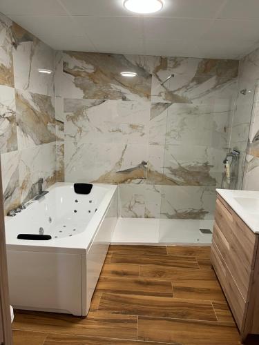 a bathroom with a white tub and a marble wall at Apartamentos Rurales El Rincón de la Sierra 