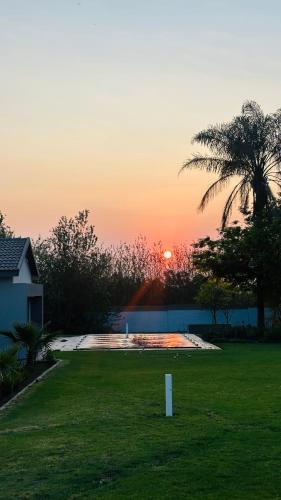 a sunset in a yard with a palm tree at Thandekile Garden Venue in Midrand