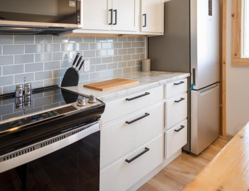 a kitchen with white cabinets and a stove at Beach Cabin 1 in Chéticamp