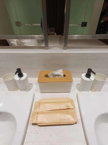 a bathroom counter with two cups and a box of toiletries at Novotel Manila Residence Hotel by Jolly Luxe Suites at Acqua in Manila