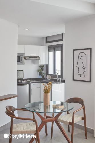 une cuisine avec une table en verre et des chaises dans une pièce dans l'établissement Stayhere Casablanca - Gauthier 2 - Contemporary Residence, à Casablanca