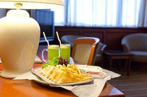 a plate of food with chips and a drink on a table at Park Avenue Hotel Sungai Petani in Sungai Petani