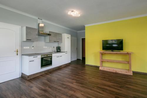 a kitchen with white cabinets and a yellow wall at Franzlhof Appartements in Stainz