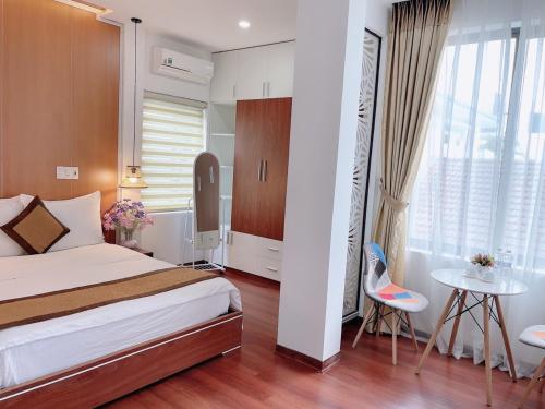 a bedroom with a bed and a table and a window at Nana Homestay & Villa in Hue