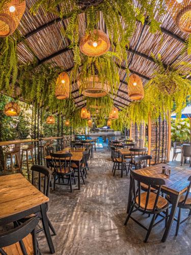 a restaurant with wooden tables and chairs and chandeliers at Hotel Casa de Hadas in Minca