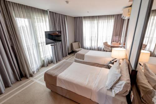 a hotel room with two beds and a television at Hotel Cadoro São Paulo in Sao Paulo