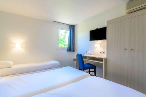 a hotel room with two beds and a desk at Comfort Hotel Orleans Saran in Saran