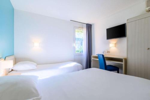 a hotel room with two beds and a chair at Comfort Hotel Orleans Saran in Saran