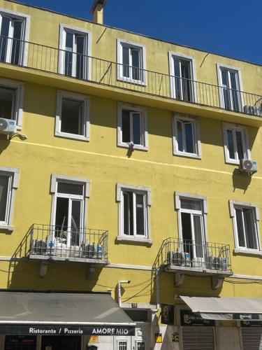 a yellow building with white windows and balconies at Lisbora Hostel Daora in Lisbon