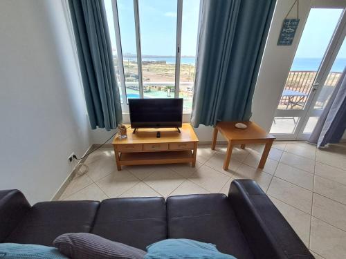 a living room with a couch and a table with a television at BriMar Holidays in Rabil