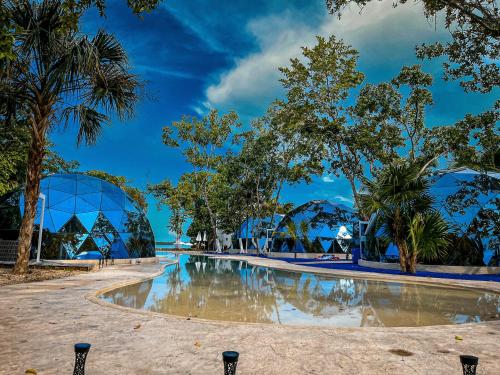 a swimming pool with trees and a building in the background at Hotel Glamping Horizonte Maya in Chetumal