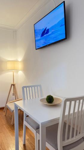 a white table with two chairs and a tv on a wall at Horizonte da Vinha in Santo Tirso