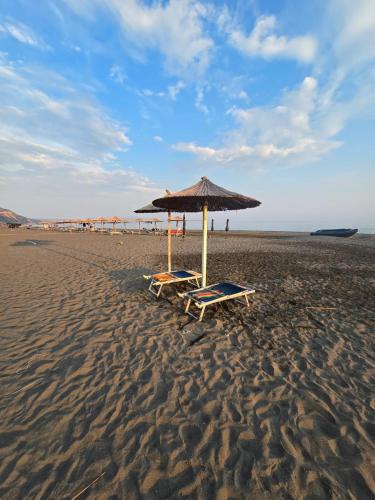 two lounge chairs and an umbrella on a beach at Villa 176 in Baks-Rrjoll