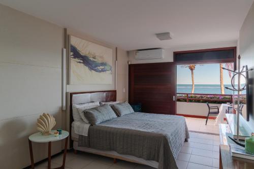 a bedroom with a bed and a view of the ocean at Casa Manaua in Barra de São Miguel