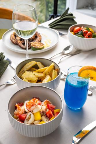 a table with three bowls of food and a glass of wine at Q Boutique Resort Malindi in Malindi