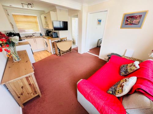 ein Wohnzimmer mit einem roten Sofa und einer Küche in der Unterkunft 2 Bedroom Chalet SB144, Sandown Bay, Isle of Wight, Dog Friendly, Free Wifi in Brading