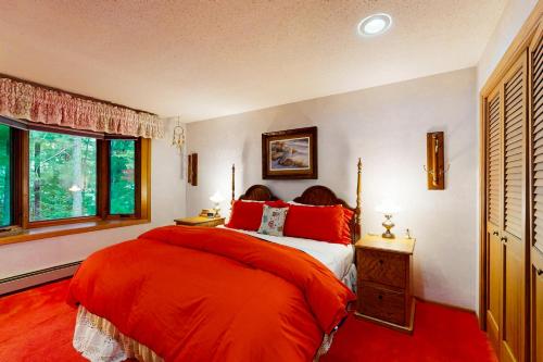 a bedroom with a bed with red sheets and a window at Lakefront Haven in Lake Tomahawk